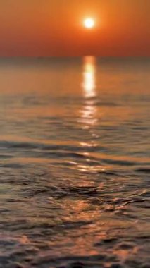 Sakin okyanus dalgalarının üzerinde yükselen altın güneş