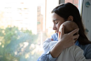 Yeni anne yeni doğmuş bebeğine şefkatle sarılıyor, şefkat ve güçlü bir bağ gösteriyor.