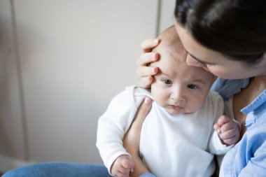 Anne ağlayan bebeği teselli ediyor, sevgi ve şefkat ifade ediyor.