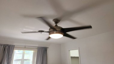 Bu görüntü, sabit pozisyonda duran gümüş tavanlı bir vantilatör yakalıyor. Fotoğraf modern tasarım, metalik yüzey ve aydınlatma işlevselliğine odaklanıyor. İç mekan ve konut temalarını temsil eder.