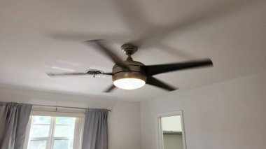 Bu statik fotoğrafta gümüş kaplama ve dahili ışığa sahip sabit bir tavan vantilatörü gösteriliyor. Vantilatör dönmüyor, tasarım ve ışıklandırma özelliğinin net görünmesini sağlıyor. Görüntü modern ev aletlerini, iç konforu, havalandırmayı temsil ediyor.