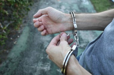 Metal kelepçeleri anahtarla açan erkek ellerinin yakın çekimi. Tutuklanma, suç, yasa uygulama, gözaltı veya özgürlük kavramı.