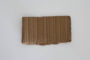 İnsan eli beyaz arka planda bükülmüş bir karton parçası tutuyor. Paketleme, geri dönüşüm ve malzeme kavramı.