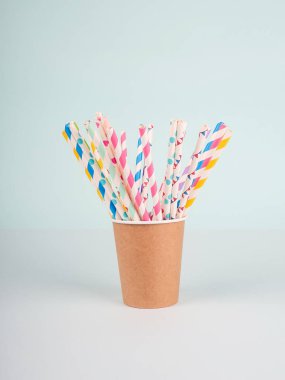 Mavi arkaplanda renkli pipetlerle Kraft kağıt bardağı.