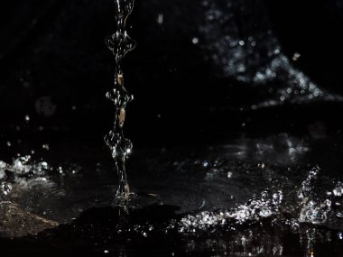 Siyah arka planda su sıçraması. Koyu cam dokuda bir damla su..