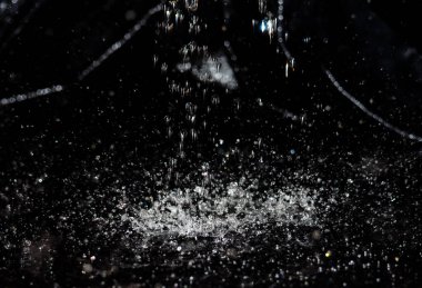 Siyah arka planda su sıçraması. Koyu cam dokuda bir damla su..