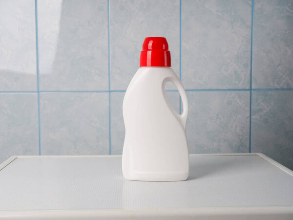 Бутылка моющего средства и чистые полотенца на стиральной машине в помещении, место для текста. День прачечной.