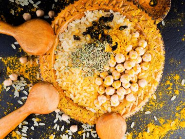 Hint ve diğer baharatlar tahta kaşıklarda, siyah bir masaya saçılmış.