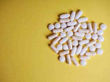 Sarı arka planda bir sürü beyaz tablet, sağlık ve ilaç kavramı