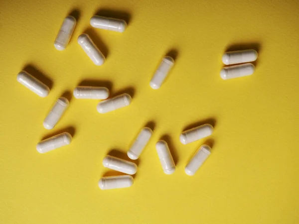 Um monte de comprimidos brancos diferentes em um fundo amarelo, o conceito de saúde e medicina — Fotografia de Stock