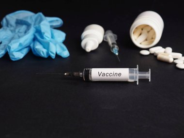 Siyah arka planda aşı olan tıbbi şırınga, tıbbi şırıngalar, eldivenler ve iğneler