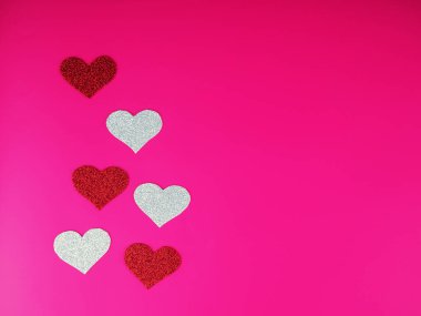 Sevgililer Günü konsepti, pembe arka planda gümüş ve kırmızı kalp, tebrik kartı.