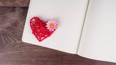 Ahşap masa arkasında kırmızı kalp şekilli boş defter ve kalem. Düğün, Romantik ve Mutlu