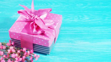 Ahşap zemin üzerinde pembe bir fiyonk olan bir hediye kutusu, metin alanının kopyası..