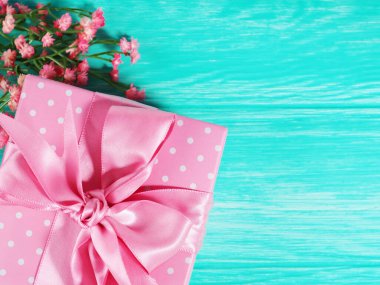 Ahşap zemin üzerinde pembe bir fiyonk olan bir hediye kutusu, metin alanının kopyası..