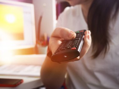 Eller televizyonun uzaktan kumandasını tutuyor, eve yakın çekim..