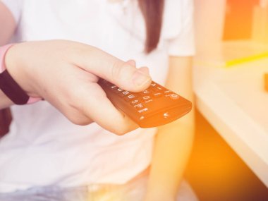 Eller televizyonun uzaktan kumandasını tutuyor, eve yakın çekim..