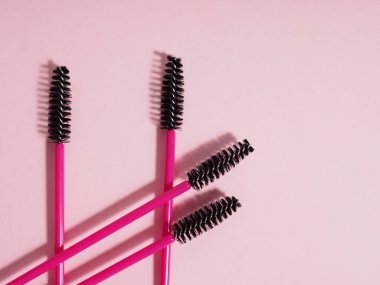 Kopyalama alanı olan pembe bir arka planda pembe kirpik fırçaları.
