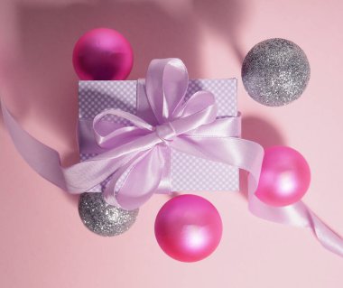 Pembe balonlarla çevrili mor kurdeleli hediye kutusu..