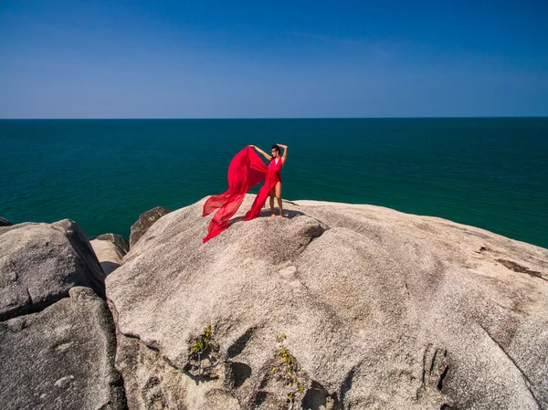 Женщина на камне в красном платье — стоковое фото