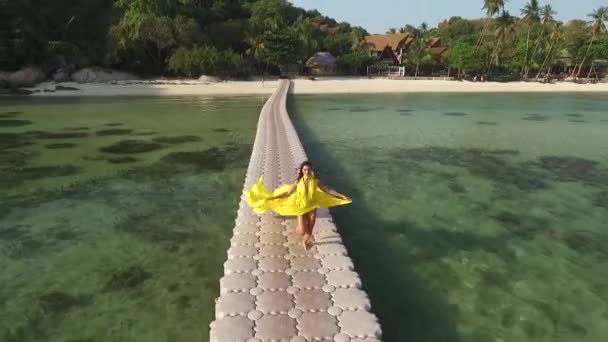 Mulher voadora em um vestido amarelo correndo pela ponte do pontão — Vídeo de Stock