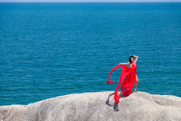 Femme en robe jaune volant sur un rocher — Photo