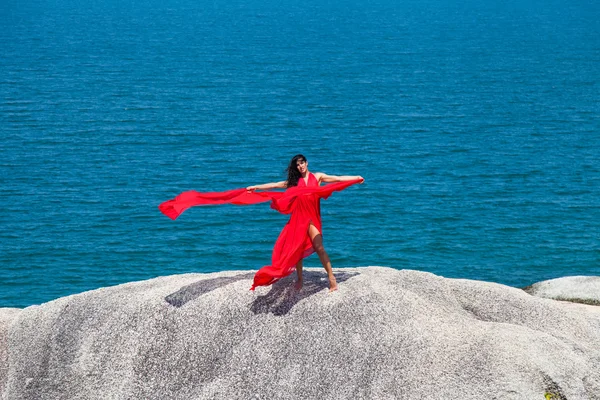 Femme en robe jaune volant sur un rocher — Photo