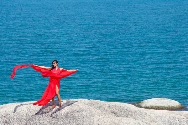 Femme en robe jaune volant sur un rocher — Photo