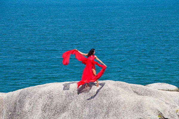 Femme en robe rouge volant sur un rocher — Photo