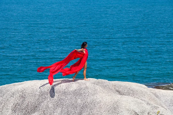 Femme en robe rouge volant sur un rocher — Photo