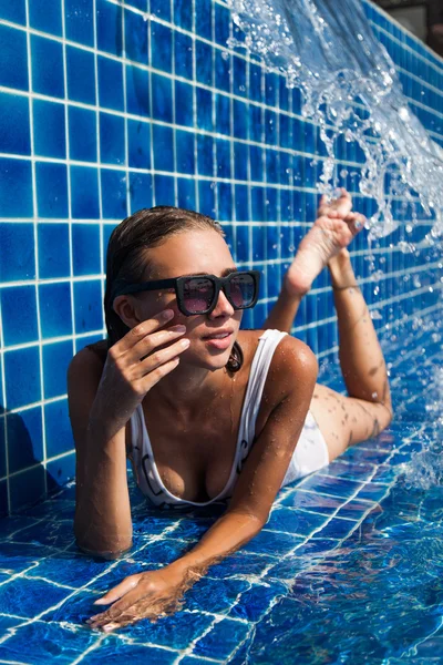 Frau im Badeanzug liegt in blauem Pool — Stockfoto