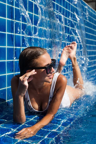 Жінка в купальнику лежить у блакитному басейні — стокове фото
