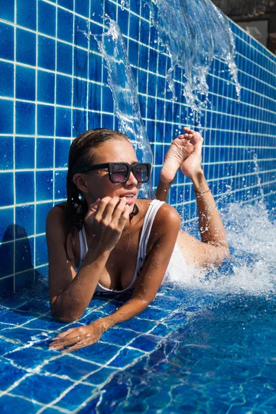 Kobieta w kostiumie kąpielowym, leżącego w niebieski basen — Zdjęcie stockowe
