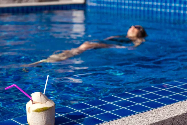 파란 수영장 코코넛와 검은색 수영복 여자 — 스톡 사진