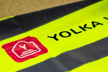 MOSKOW, Rusya - 16 ARALIK 2020 YOLKA WMS rozet Sarı sinyal yelek yakın görüş. Yolka Depo yönetim sistemi. Depo binasında bir paletin ve kutuların üzerinde duran işaret yeleği..