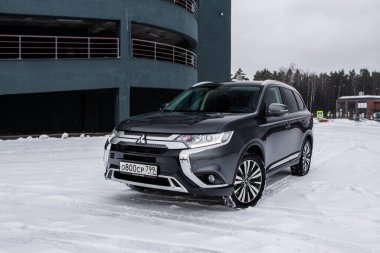 MOSCOW, Rusya - 30 Ocak 2021 Mitsubishi Yabancısı. Mitsubishi Motors tarafından üretilen üçüncü nesil Japon kompakt arazi aracı. Model yıl 2020. Karanlık Mitsubishi kışın arka planda. Ön taraf yakın görünüm.