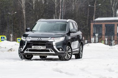 MOSCOW, Rusya - 30 Ocak 2021 Mitsubishi Yabancısı. Mitsubishi Motors tarafından üretilen üçüncü nesil Japon kompakt arazi aracı. Model yıl 2020. Karanlık Mitsubishi kışın arka planda. Ön taraf yakın görünüm.