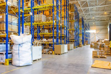 Üst raflarda sıra sıra eşya kutuları olan modern bir deponun içinde.