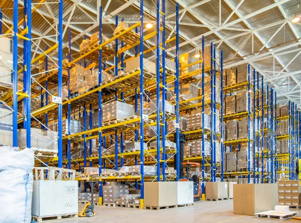 Üst raflarda sıra sıra eşya kutuları olan modern bir deponun içinde.