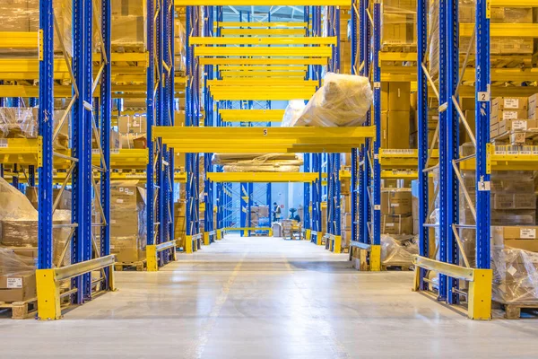 Üst raflarda sıra sıra eşya kutuları olan modern bir deponun içinde.