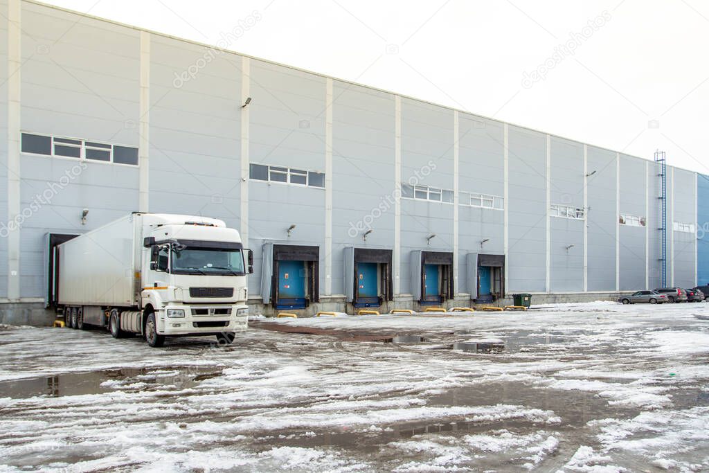 Truck while loading in a big distribution warehouse with gates for for loading goods and trucks 