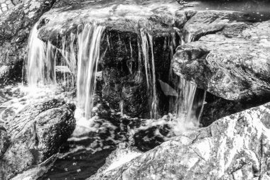 Monochrome waterfall scene with dynamic water flow and textured rocks, ideal for nature and fine art themes