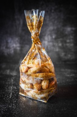 Geleneksel ev yapımı vanilyalı kurabiyelerin kapanışı pudra şekerli tozlu, hassas dokuyu vurgulayan, ev yapımı cazibe ve şeffaf bir hediye paketinde sunulan sıcak, şenlikli tatlı atmosferi.