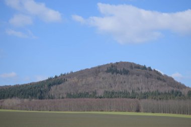 Baharda açık mavi bulutlu gökyüzünün altındaki yeşil tepelerin güzel manzarası.