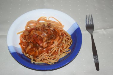 Beyaz tabakta et ve sebzeli spagetti.