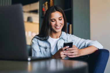 Çekici iş kadını dizüstü bilgisayarın önünde oturuyor ve cep telefonuyla konuşuyor, telefonda görüşüyor.. 
