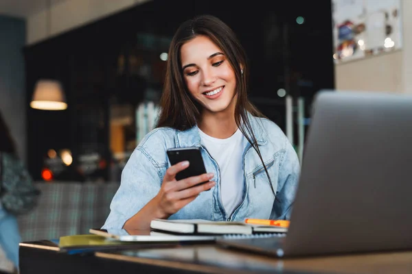Çekici iş kadını dizüstü bilgisayarın önünde oturuyor ve cep telefonuyla konuşuyor, telefonda görüşüyor.. 