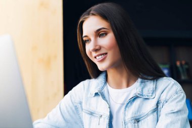 İş kadını dizüstü bilgisayarın önünde oturuyor, online eğitim alıyor, ev ofisinden çalışıyor. Yakın plan portre.