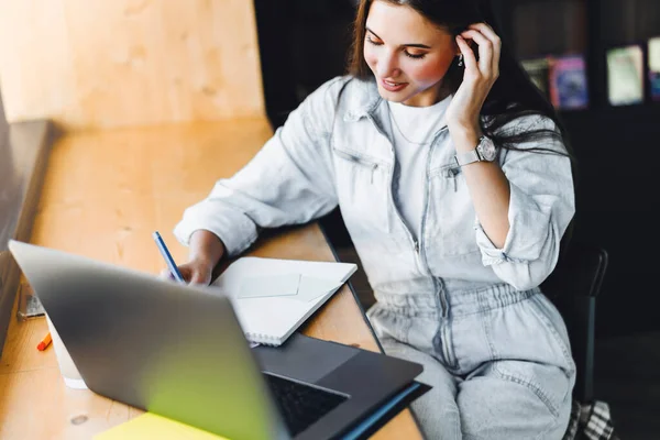 Aantrekkelijke zakenvrouw zit aan tafel voor laptop. Mooie brunette meisje glimlacht, Online training — Stockfoto