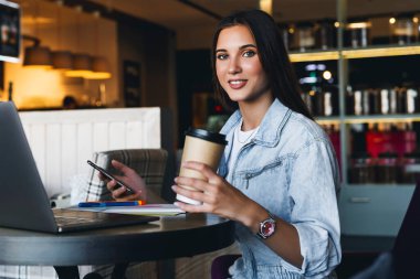 Çekici iş kadını dizüstü bilgisayarın önünde oturuyor ve cep telefonuyla konuşuyor, telefonda görüşüyor.. 